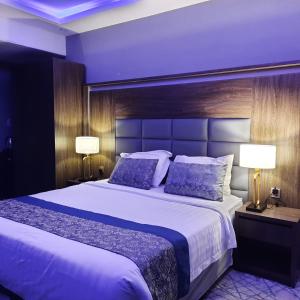 a bedroom with a large bed and two lamps at Swat Hotel Apartments 2 in Al Khobar