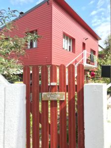 a wooden fence in front of a red house at La Maison Rouge in Trouville-sur-Mer