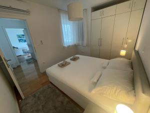 Un dormitorio con una gran cama blanca con zapatos. en Apartman SeaSide, en Zadar