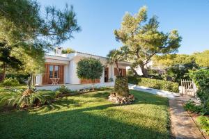 a house with a yard with green grass and trees at Miloca 2 in Playa de Muro