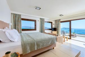 a bedroom with a bed and a large window at Elounda Ilion Hotel Bungalows in Elounda