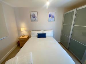 a bedroom with a large white bed with a blue laptop on it at Cozy 2 bed Flat in Southwark, Near Canary Wharf in London