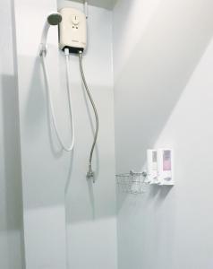 a shower in a white bathroom with a blow dryer at Cooper in Bangkok