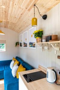 a living room with a blue couch and wooden ceilings at Enchanting Tiny House with wood burner and hot tub in Cairngorms in Ballater