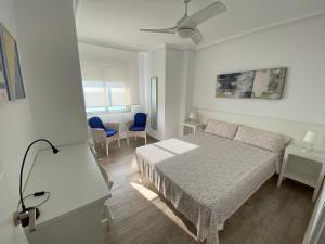 1 dormitorio blanco con 1 cama y ventilador de techo en Emilia's Cabin, en Guardamar del Segura