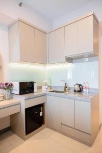 a kitchen with white cabinets and a microwave at ermina at benson pakuwon mall in Surabaya