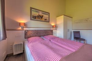 a bedroom with a bed with a pink checkered blanket at Ferienhof Brandt in Hedwigenkoog