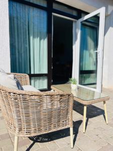 a wicker chair and a glass table on a patio at Ikšķiles apartamenti 2 in Ikšķile