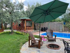 un patio con 2 sillas y una sombrilla verde en Tiny House Village en İznik