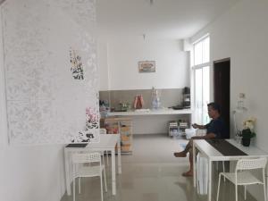 a man sitting at a table in a room at Ambarukmo Green Hill / MA 8 in Yogyakarta