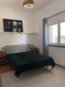 een slaapkamer met een groen bed en een raam bij House of green leaves in Chelreira