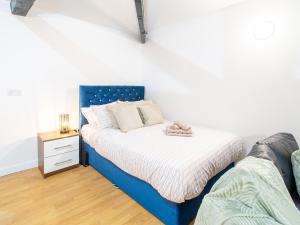 a bedroom with a blue bed and a night stand at Spacious Studio with Parking - 10 Mins to Leeds Centre in Leeds