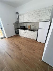 een keuken met witte apparatuur en een houten vloer bij AMANTIUS APARTMENTS in Borsh