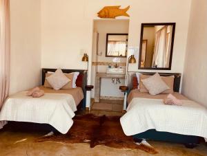 2 Betten in einem Zimmer mit Spiegel und Waschbecken in der Unterkunft Kuvira River Camp in Divundu
