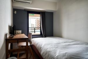 福岡的住宿－Hotel STARRIZE，一间卧室配有一张床、一张书桌和一个窗户。
