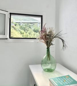 un jarrón con flores en una mesa frente a una ventana en Casita Juan Carro, un oasis de paz!, en Puntallana