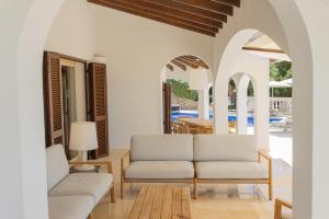 a living room with white furniture and a pool at Villa Maitreya By MENORCARENTALS in Son Bou