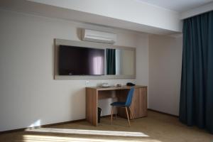 Cette chambre comprend un bureau et une télévision murale. dans l'établissement Hotel Regal, à Braşov