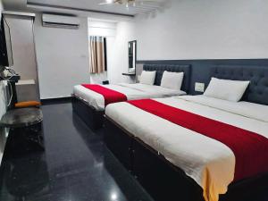 a hotel room with two beds with red and white sheets at STAYMAKER Hotel Hill View in Madikeri
