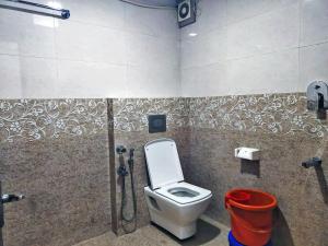 a bathroom with a toilet and a red bucket at Hotel Hill View in Madikeri