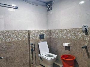a bathroom with a toilet and a red bucket at STAYMAKER Hotel Hill View in Madikeri