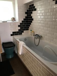 a bathroom with a white tub and black tiles at La Maison Rouge in Trouville-sur-Mer +18 photos