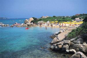 馬里內拉的住宿－Residence with private beach in Marinella，一群人在海滩上,带遮阳伞