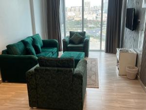 sala de estar con muebles verdes y ventana grande en Gulf grand hotelجلف جراند اوتيل, en Kuwait