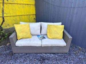 a couch with two yellow pillows and a book on it at Boss Fab4 Stay &Garden Pro Host in Liverpool
