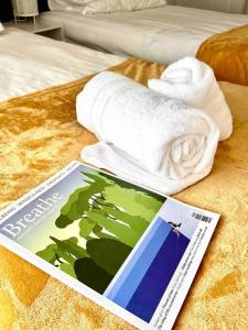 een tijdschrift en handdoeken op een bed bij Boss Fab4 Stay &Garden Pro Host in Liverpool