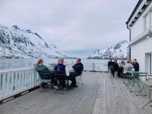 a group of people sitting at tables on a deck at Northstay - House of Northern Lights in Tromsø
