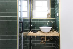 Un baño de azulejos verdes con lavabo y espejo. en Castelo Premium by Homing, en Lisboa 68 fotos más