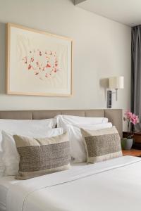 里斯本的住宿－多卡洛斯公園酒店，白色的床铺、白色的枕头和墙上的绘画