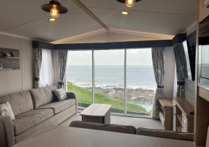 a living room with a couch and a view of the ocean at Braddicks Holidays - Sea View Apartments & Caravans in Westward Ho