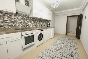 a kitchen with white cabinets and a washer and dryer at Golden Homes in Bostancı