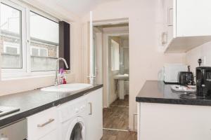 a white kitchen with a sink and a washing machine at City Rooms in Stoke City in Stoke on Trent