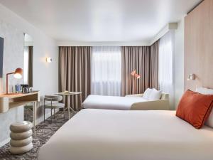 a hotel room with two beds and a desk at Novotel Paris 13 Porte d'Italie in Le Kremlin-Bicêtre