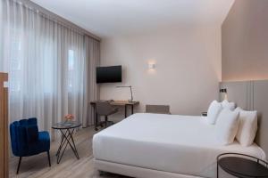 ein Hotelzimmer mit einem großen weißen Bett und einem Schreibtisch in der Unterkunft NH Trieste in Triest