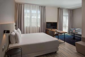 una camera d'albergo con un grande letto e una scrivania di NH Trieste a Trieste