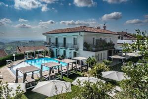 a villa with a swimming pool and tables and umbrellas at Villa Nonna Cicci Boutique Hotel - SPA in Cisterna dʼAsti