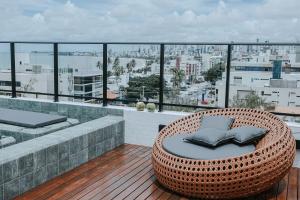 einen Rattansessel auf einem Balkon mit Stadtblick in der Unterkunft Flats na praia do Bessa in João Pessoa