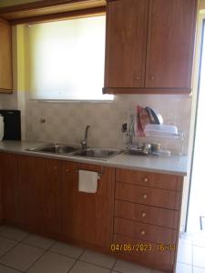 a kitchen with wooden cabinets and a sink and a window at Anna's Sweet Home Akrata in Paralía Akrátas