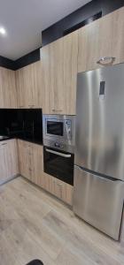 uma cozinha com um frigorífico de aço inoxidável e um micro-ondas em Apartamento La Estación - Para 6 em Avilés