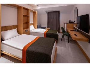 a hotel room with two beds and a desk and a television at Swandor Hotels & Resorts - Kemer in Kemer