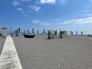 a sandy beach with palm trees and a boardwalk at Vila Plaja Azur in Eforie Nord