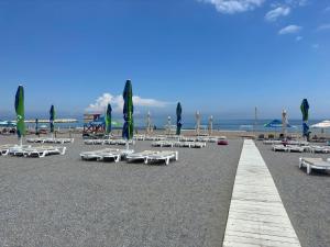 a beach with white lounge chairs and umbrellas at Vila Plaja Azur in Eforie Nord