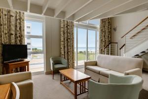 a living room with a couch and chairs and a television at Southern Sun The Marine in Port Elizabeth