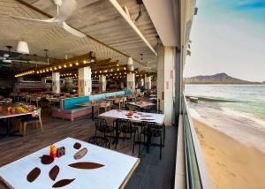 OUTRIGGER Reef Waikiki Beach Resort في هونولولو: مطعم على الشاطئ به طاولات وكراسي