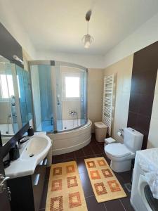 a bathroom with a tub and a toilet and a sink at Ornela's Home in Yiánnidhes