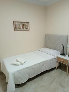 a bedroom with a white bed and a sign that reads love at Delicia, Sol y mar in Málaga